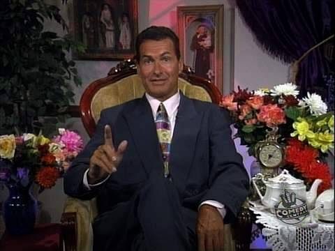 God Stuff: The Daily Show 3 A man in a suit named Joe sitting in front of flowers.