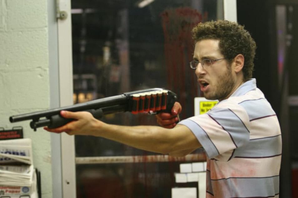 A man holding a gun in front of an auto store.